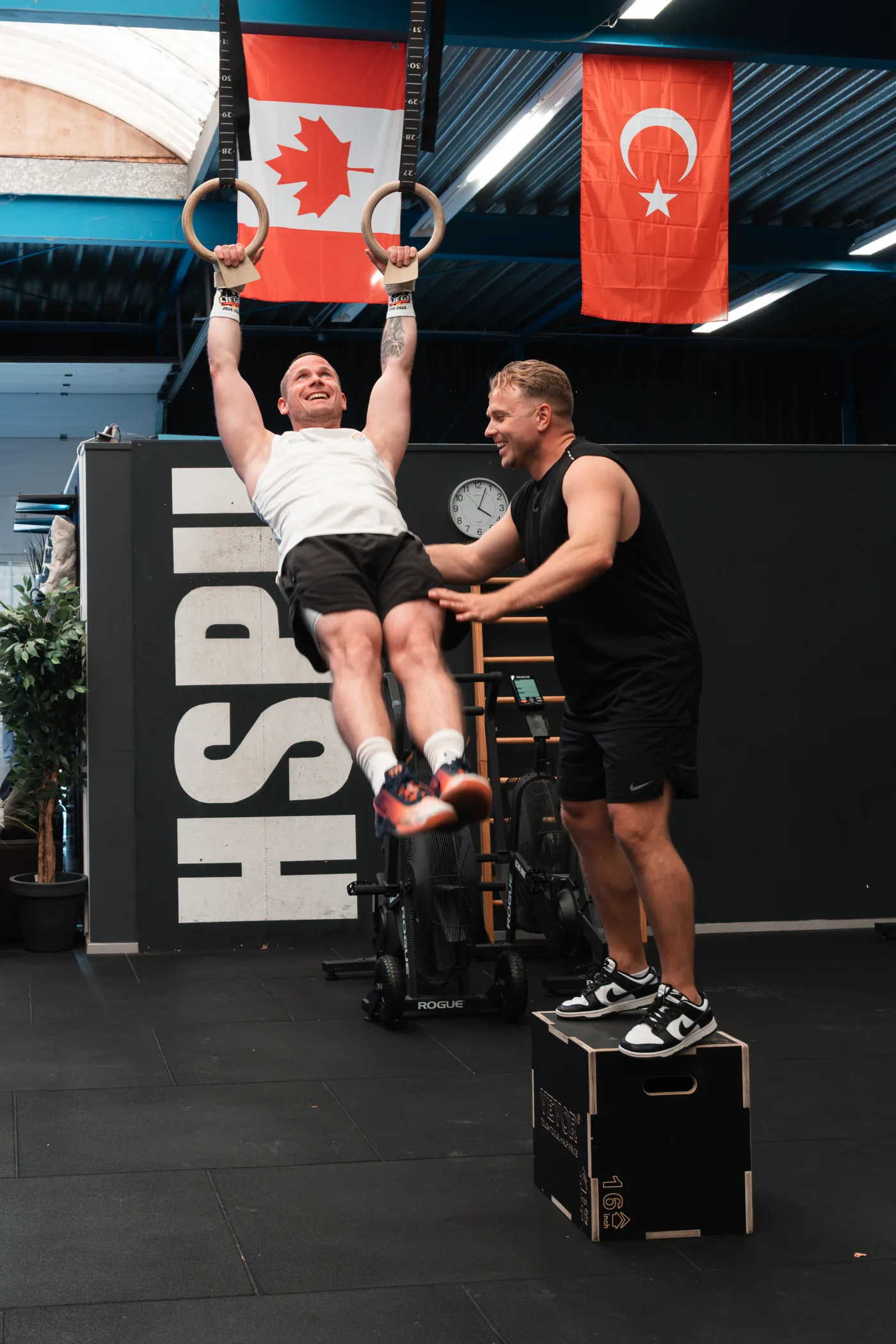 Alexander Panskus unterstützt einen Athleten beim Training an den Ringen